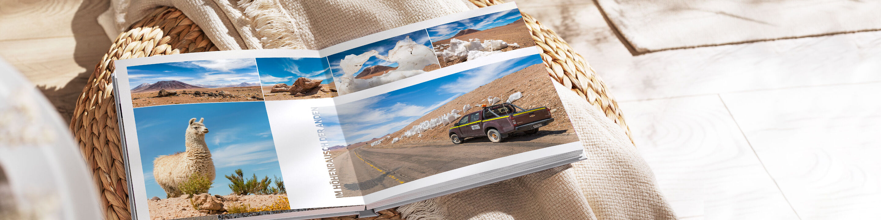 Ein offenes CEWE FOTOBUCH mit Reisebildern, darunter ein Lama, eine Straße und ein Auto in einer Landschaft.