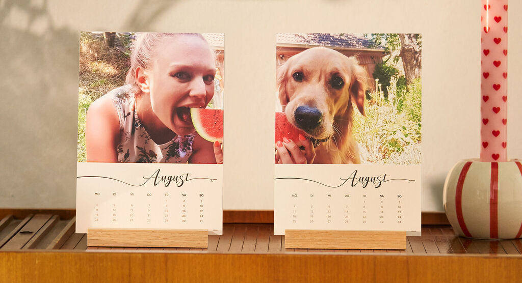 Zwei CEWE Fotokalender für August mit Mädchen und Hund, beide mit einem Stück Wassermelone