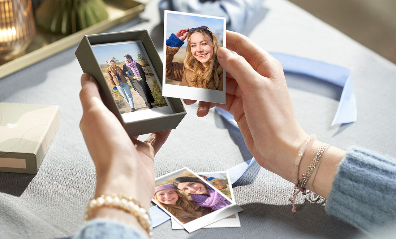 Hände präsentieren ein Geschenk mit Fotos und Erinnerungen