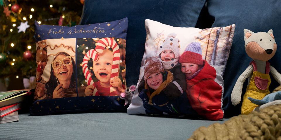 Personalisierte Fotokissen mit Weihnachtsgrüßen und fröhlichen Familienfotos auf einem Sofa.