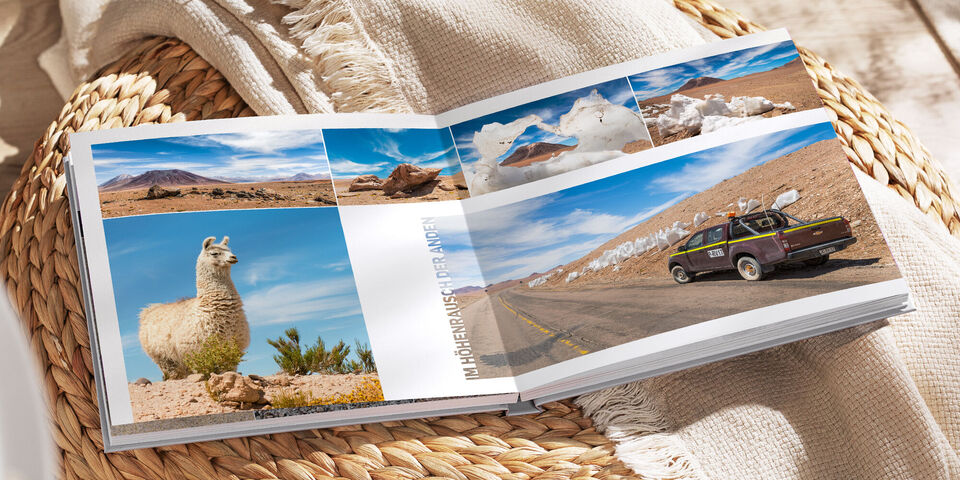 Ein geöffnetes Fotobuch zeigt Reisen, mit einem Lama, einer Straße und beeindruckenden Landschaften