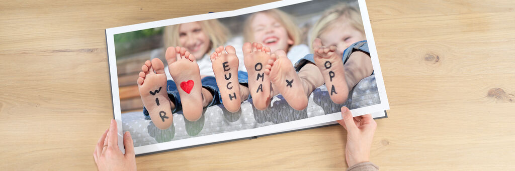 Zwei Kinderfüße mit liebevollen Botschaften auf einer Fotobuchseite, die Freude und Zusammenhalt zeigen