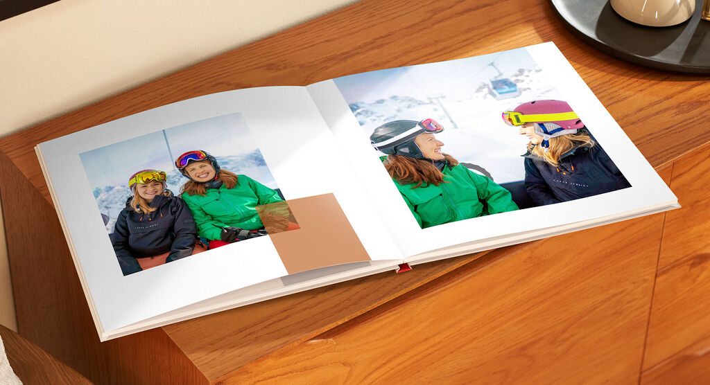 Ein offenes Fotobuch mit zwei Seiten, die fröhliche Kindergesichter zeigen. Ein unvergesslicher Moment aus dem Urlaub.
