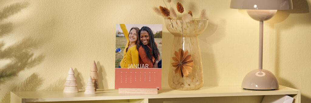 Ein Tisch mit einem stilvollen Kalender für Januar und einer Vase mit Trockenblumen.