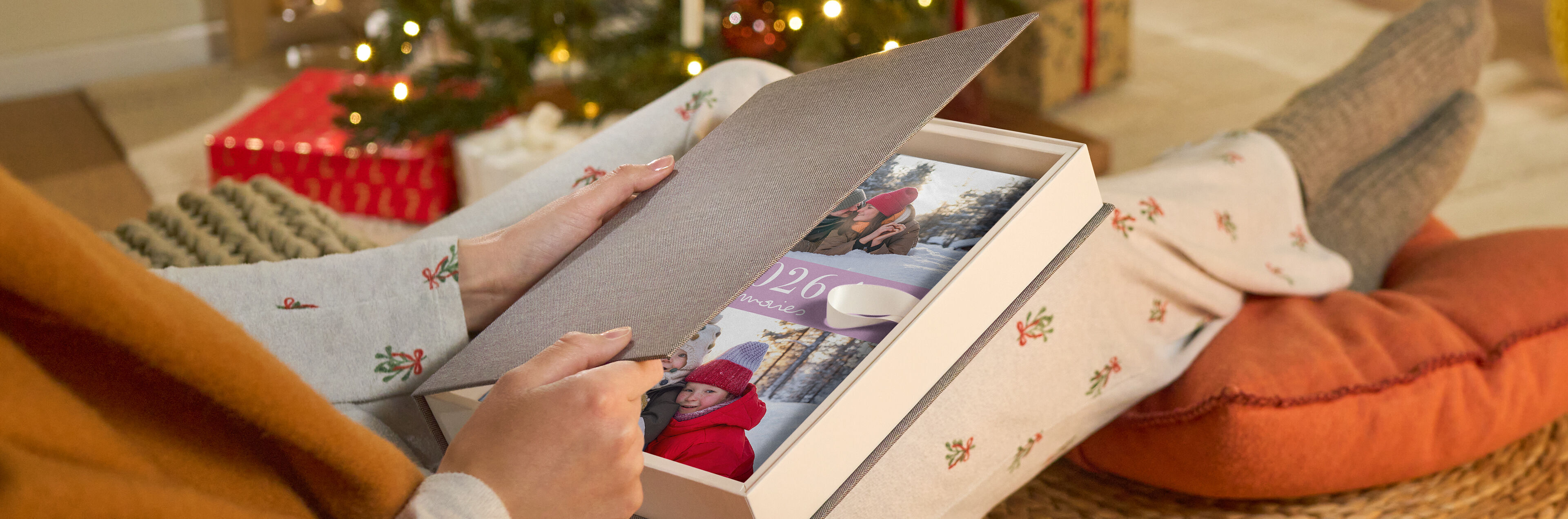 Eine Person öffnet eine Geschenkbox mit einem CEWE FOTOBUCH.