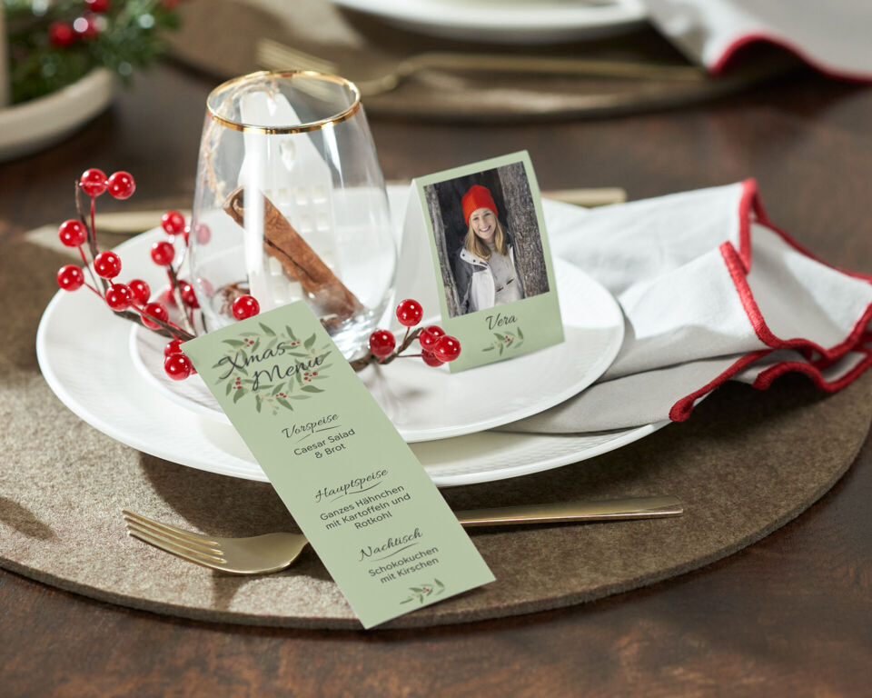 Festlich gedeckter Tisch mit Menükarte und Foto-Tischkarte mit weihnachtlichen Designs.