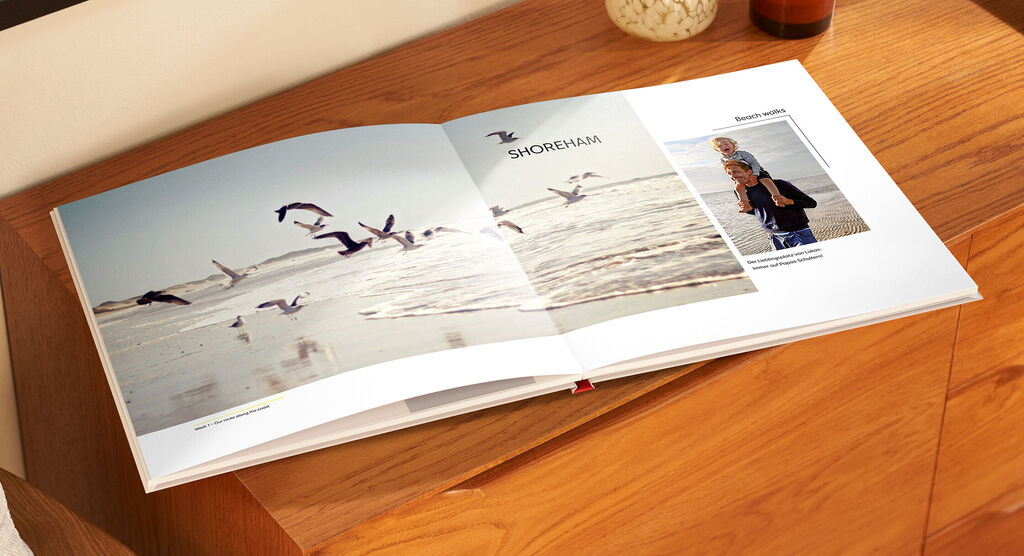 Ein offenes Fotobuch mit Bildern von Vögeln am Strand und einem Glücksmenschen.