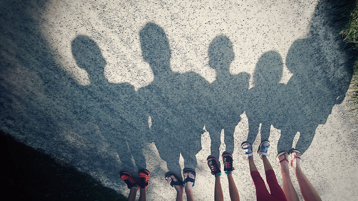 Schatten von fünf Kindern, die Hand in Hand stehen und die Sonne genießen.