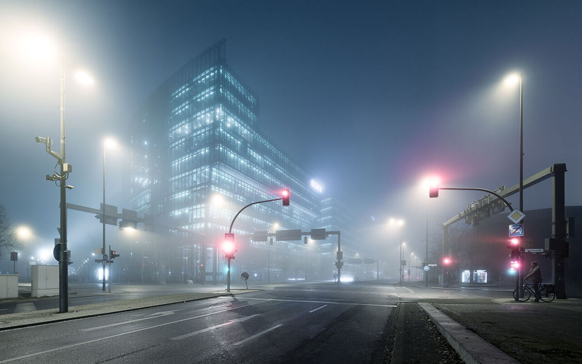Moderne Gebäude mit Glasfassade in nebliger Nacht.