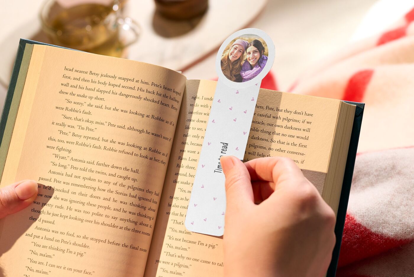 Person hält ein Buch und ein personalisiertes Foto-Lesezeichen mit einem Bild von Freundinnen und dem Schriftzug "Time to read".