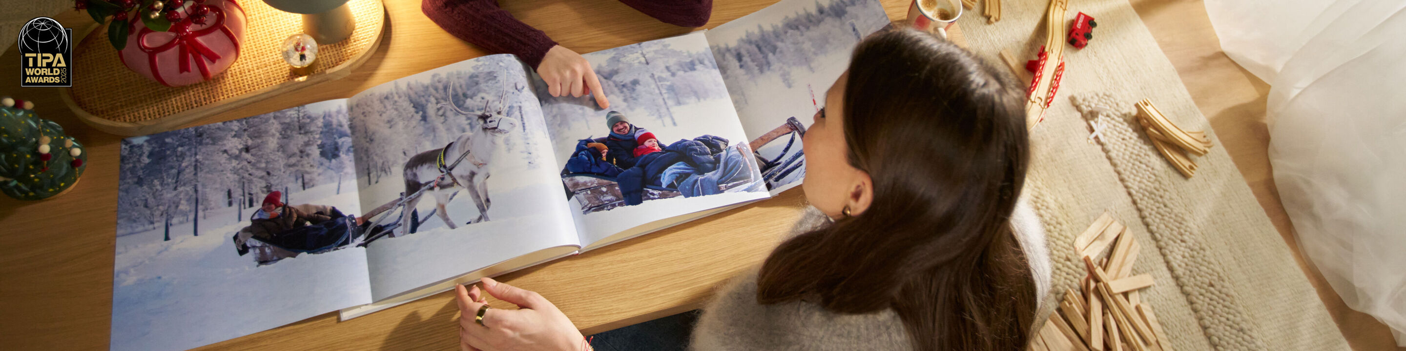 Eine Mutter und ihr Kind betrachten Familienfoto auf einer Panoramaseite in einem CEWE FOTOBUCH.