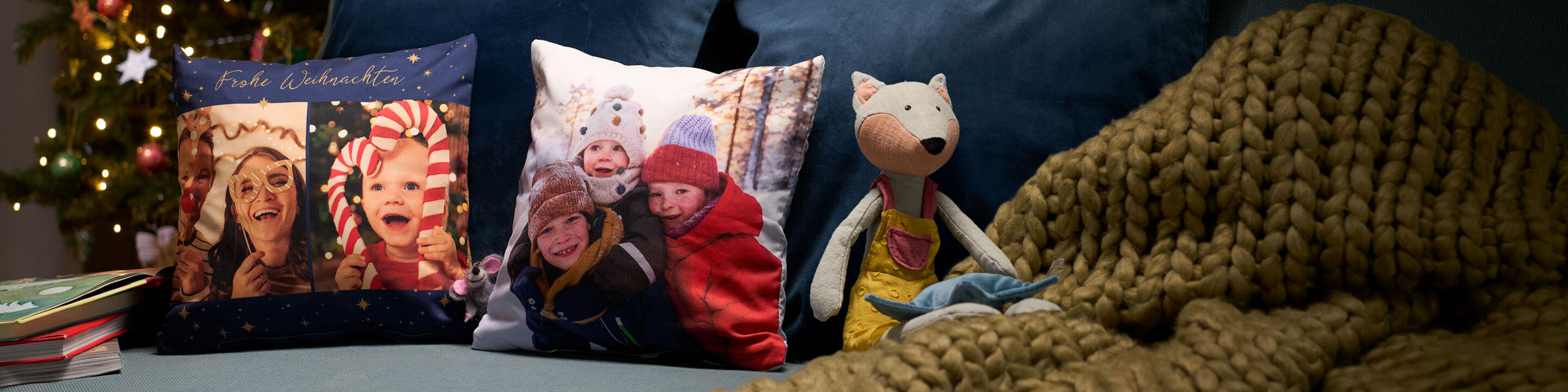 Personalisierte Fotokissen mit Weihnachtsgrüßen und fröhlichen Familienfotos auf einem Sofa.