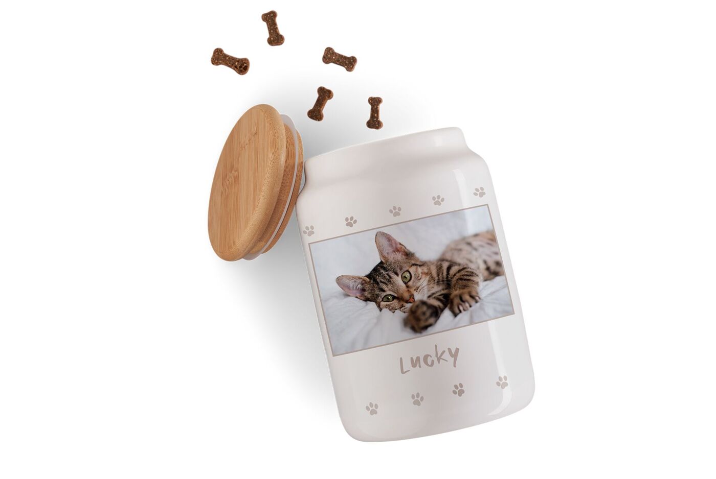 Weiße Leckerli-Dose mit Holzdeckel, Katzenfoto, Pfotenmuster und dem Schriftzug „Lucky“ neben Knochen-Leckerlis.