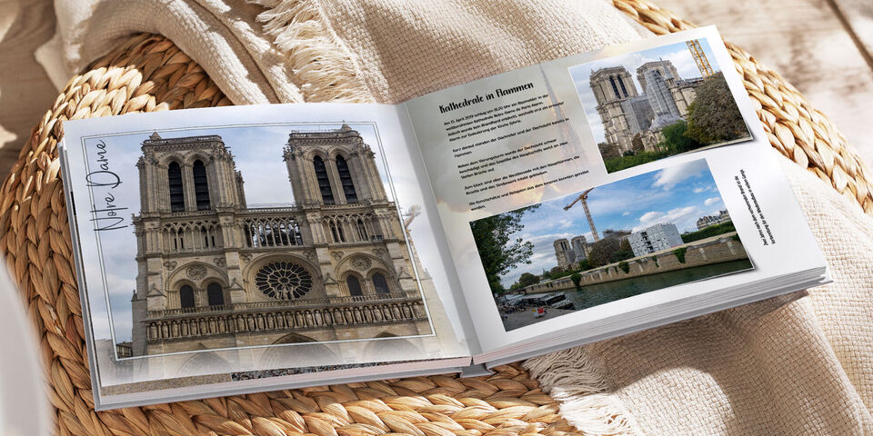 Ein geöffnetes Fotobuch liegt auf einem Tisch, zeigt die Kathedrale Notre-Dame und eine Beschreibung der Stadt.