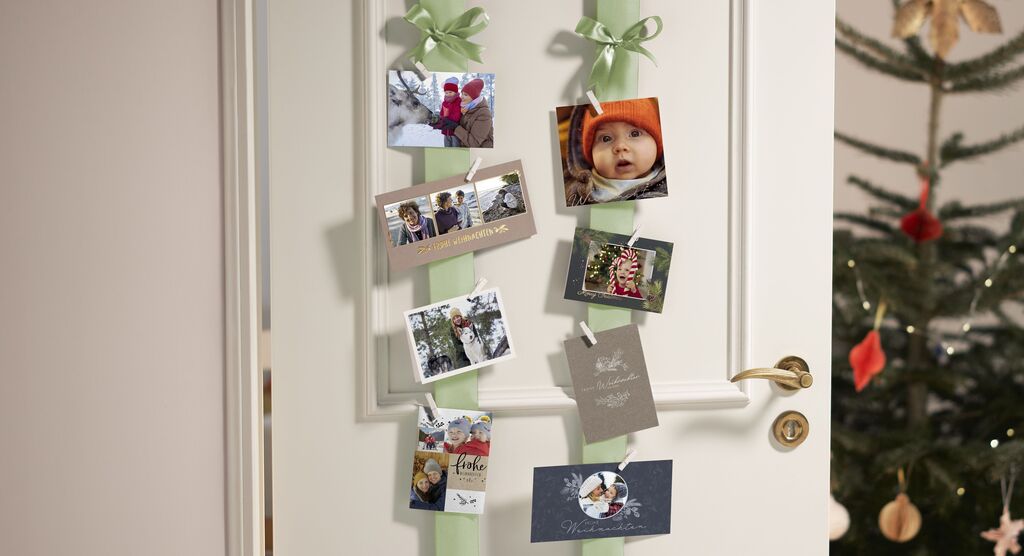 Eine Türe mit vielen gestalteten und bunten Fotos und Karten, die an Bändern hängen und für schöne Erinnerungen stehen