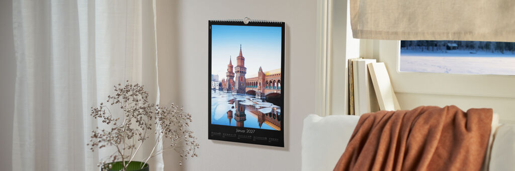 Ein CEWE Fotokalender hängt an der Wand, zeigt einen schönen Ort mit bunten Gebäuden.