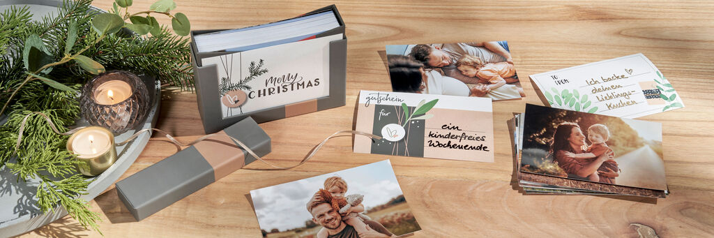 Eine liebevoll gestaltete CEWE Grußkarten-Box mit Fotos und Weihnachtskarten auf einem Holztablett.
