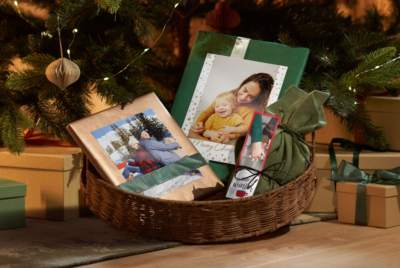 Ein Korb mit liebevoll verpackten Geschenken, darunter CEWE Fotobuch und personalisierte Grußkarten, dekoriert mit Tannenzweigen