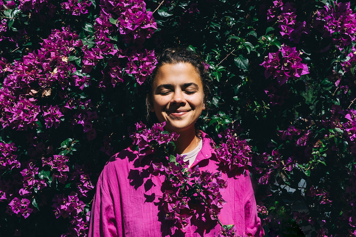 Eine Person steht vor leuchtend violetten Bougainvillea-Blüten.