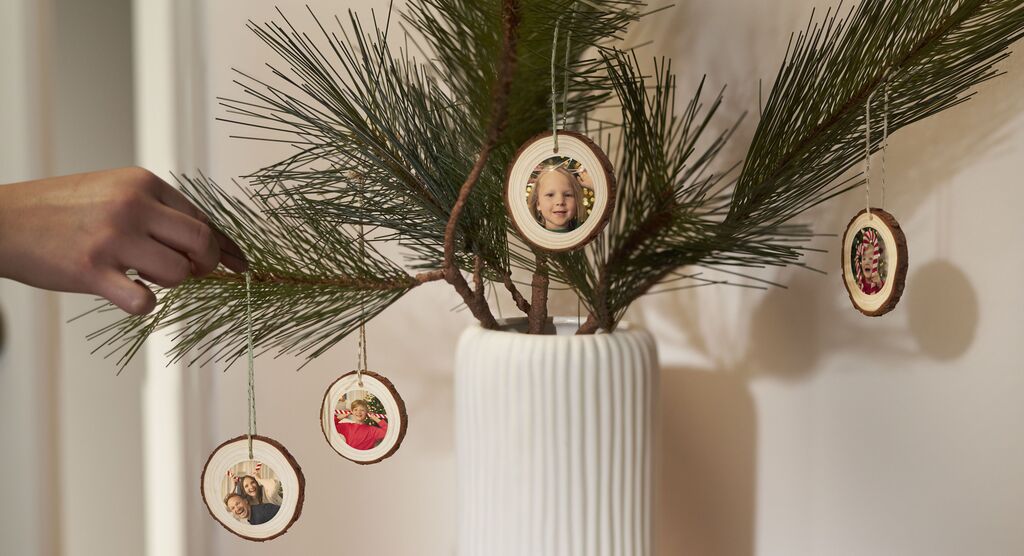 Eine Person hängt festliche Ornamente an einen Tannenbaum.