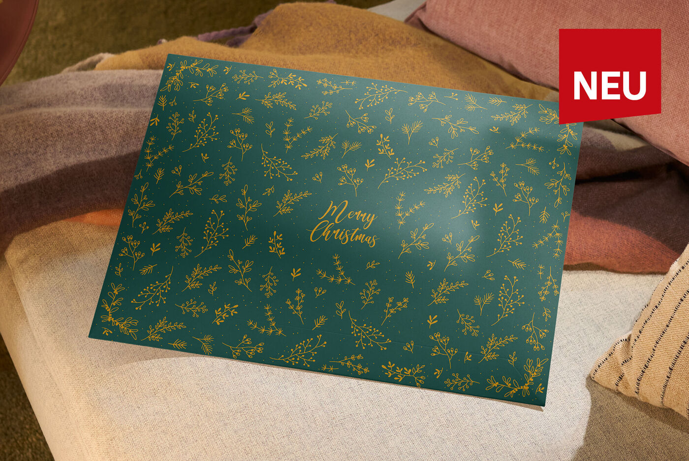 Grüne Geschenkverpackung mit der Aufschrift: Merry Christmas auf Sofa