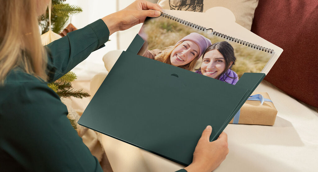 Person hält einen Fotokalender mit Bildern von glücklichen Momenten