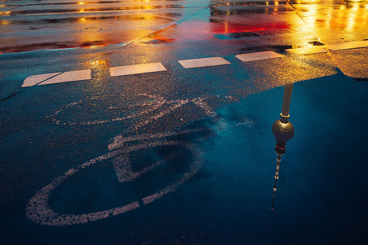 Reflexion des Berliner Fernsehturms auf nassem Asphalt mit Fahrradweg