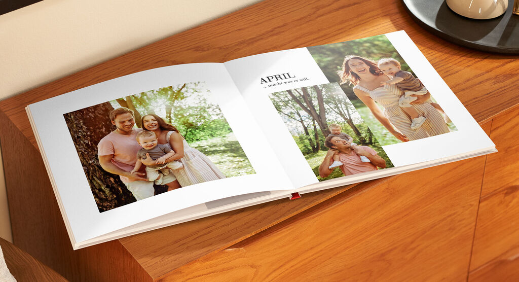 Ein offenes Fotobuch mit zwei Bildern, einer Mutter mit ihrem Kind auf einem sonnigen Tag.