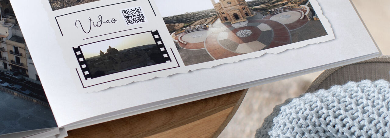 Seite eines CEWE FOTOBUCHs mit Urlaubsfotos und einem QR-Code neben dem Schriftzug "Video".