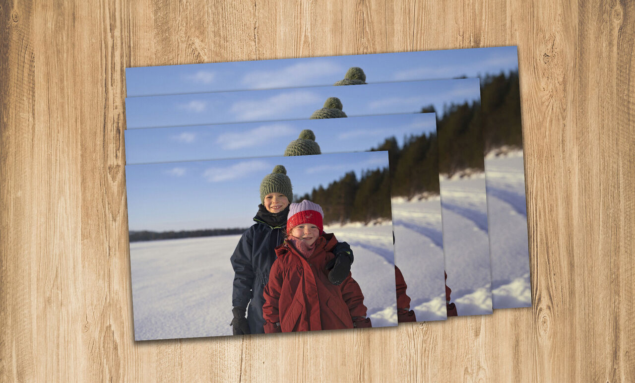 Zwei Kinder stehen fröhlich im Schnee, umgeben von einer winterlichen Landschaft.