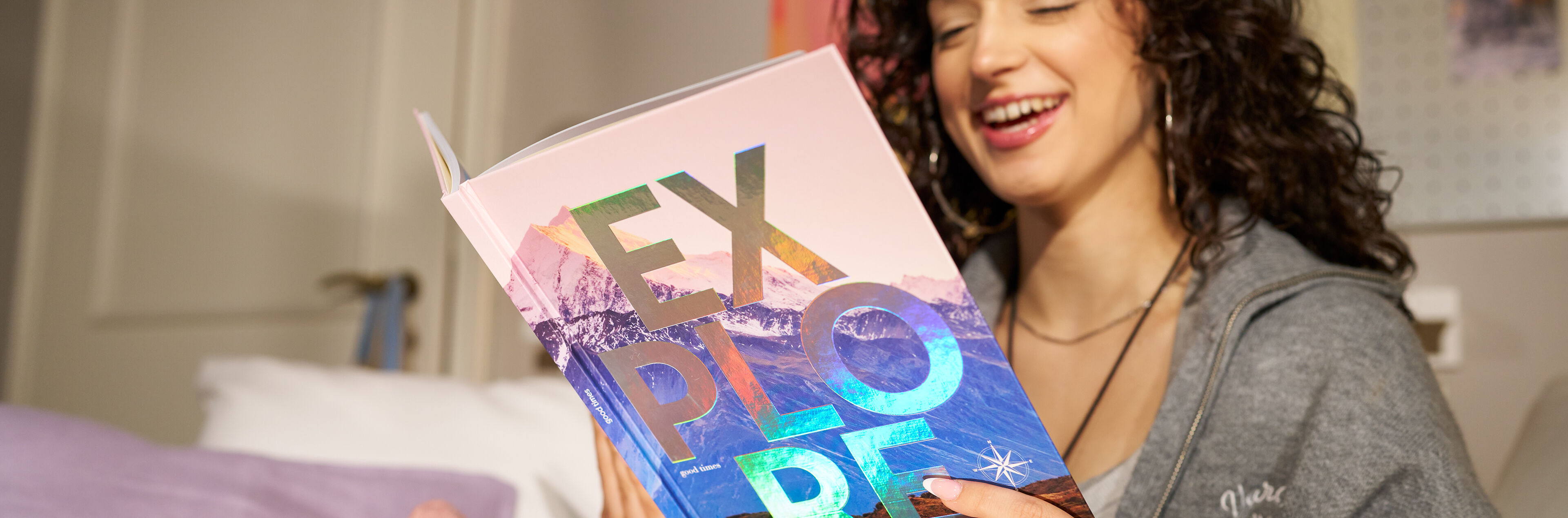 Eine junge Frau hält ein CEWE FOTOBUCH mit einer holografischen Veredelung in den Händen.