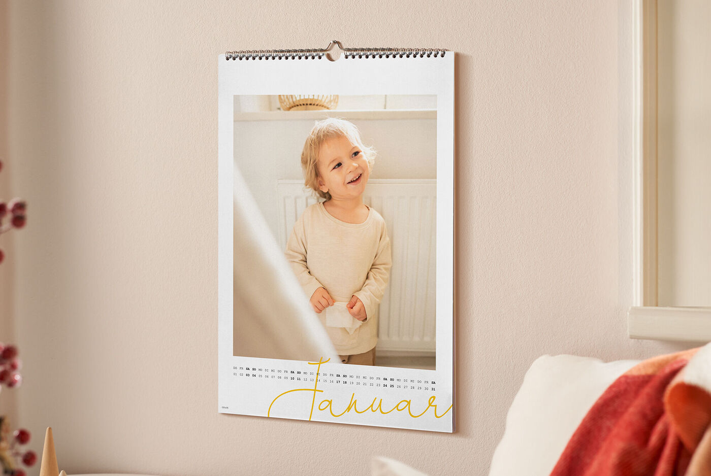 CEWE Fotokalender mit Kleinkind in heller Kleidung vor Heizkörper