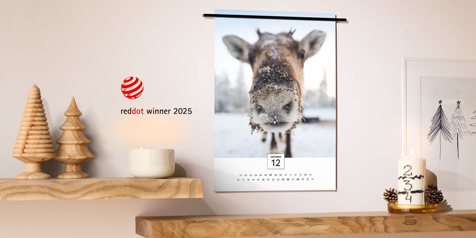 CEWE Kalender mit modernem Design, aufgehängt an einer Wand neben festlicher Dekoration wie Kerzen und Holztannen