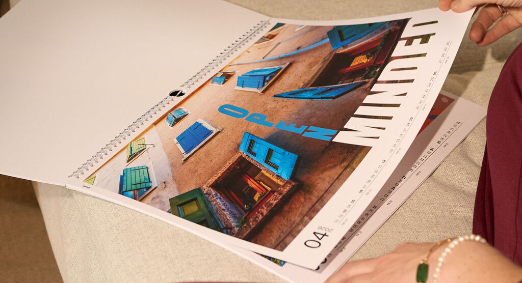 Aufgeklappter Wandkalender mit einem großen Urlaubsmotiv und dem Schriftzug „open minded“.