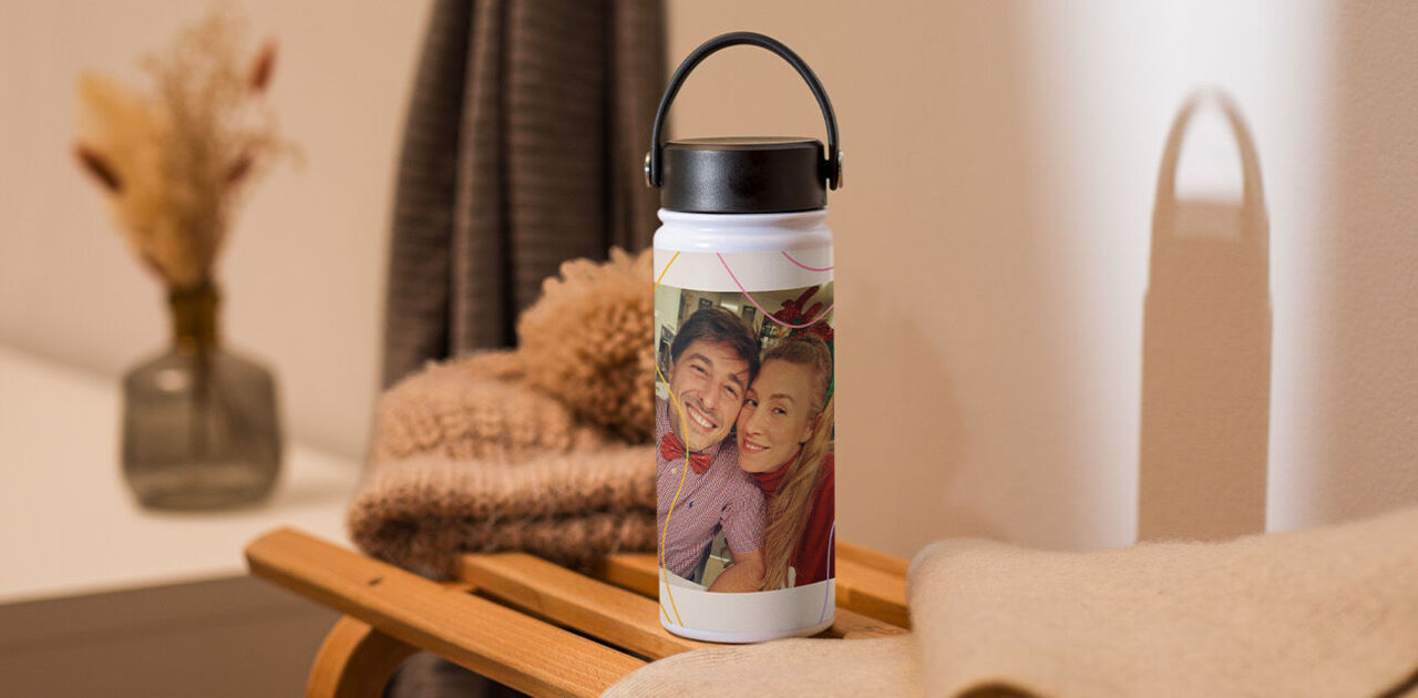 Personalisierte Trinkflasche mit dem Foto eines lächelnden Paares auf einem Holzschlitten