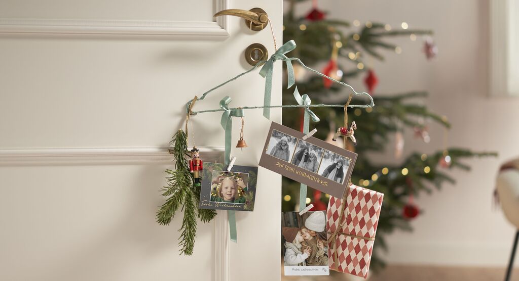 Bunte, festliche Karten und Dekoration hängen an einer Tür, umgeben von einem Weihnachtsbaum im Hintergrund